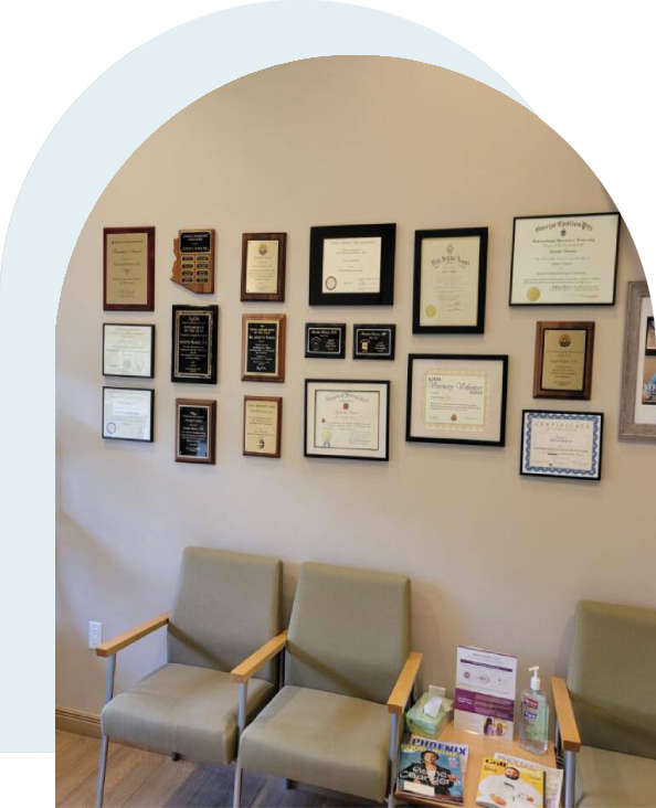 A wall with many framed certificates and medical records.
